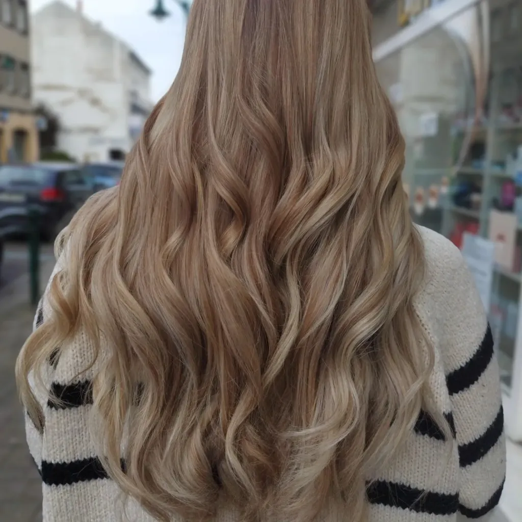 Les mêmes cheveux longs après un balayage blond beige et un coiffage ondulé