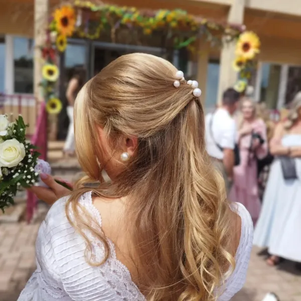 Coiffure de mariage demi-attachée, longueurs ondulées et épingles à perles, vue de dos