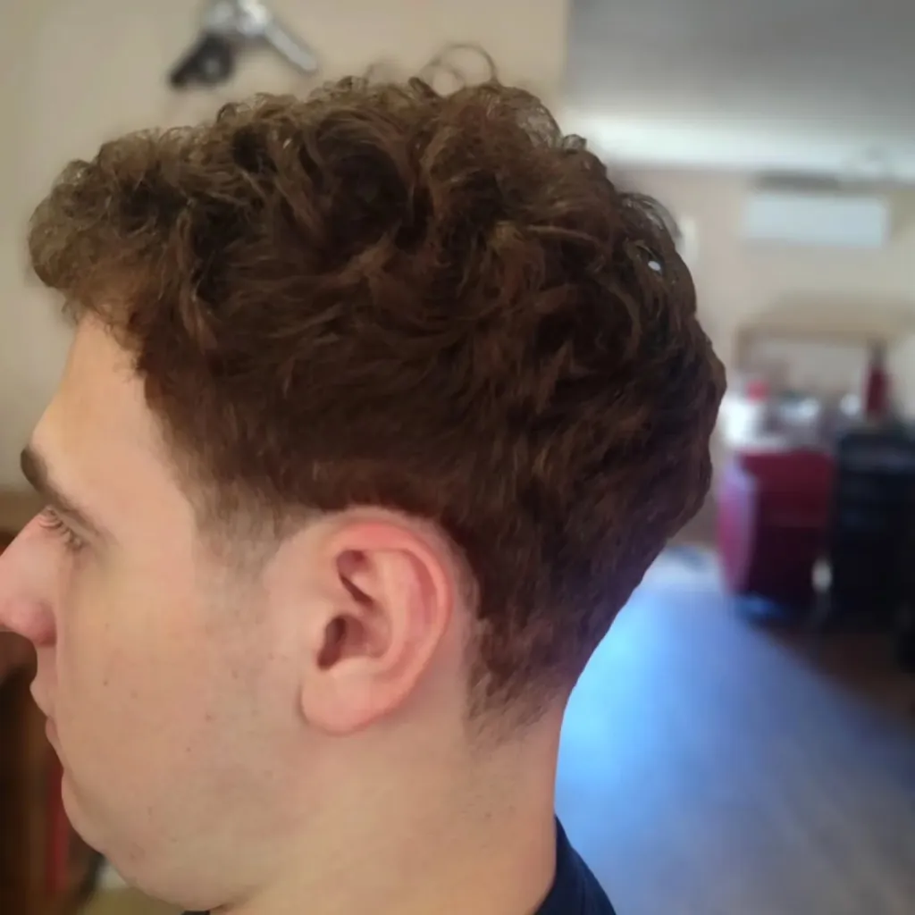 Coupe homme sur cheveux bouclés avec dégradé sur les côtés, vue de profil