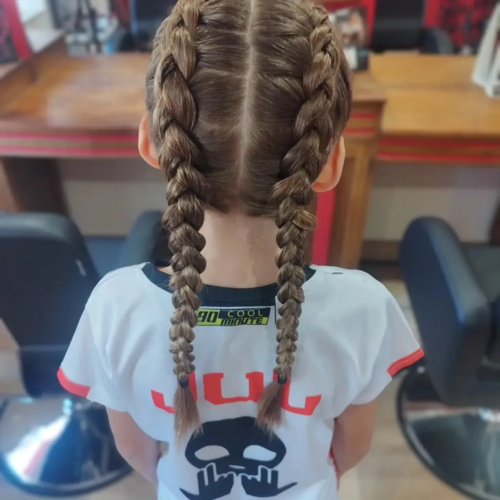 Deux tresses collées sur cheveux longs d’enfant, vues de dos au salon